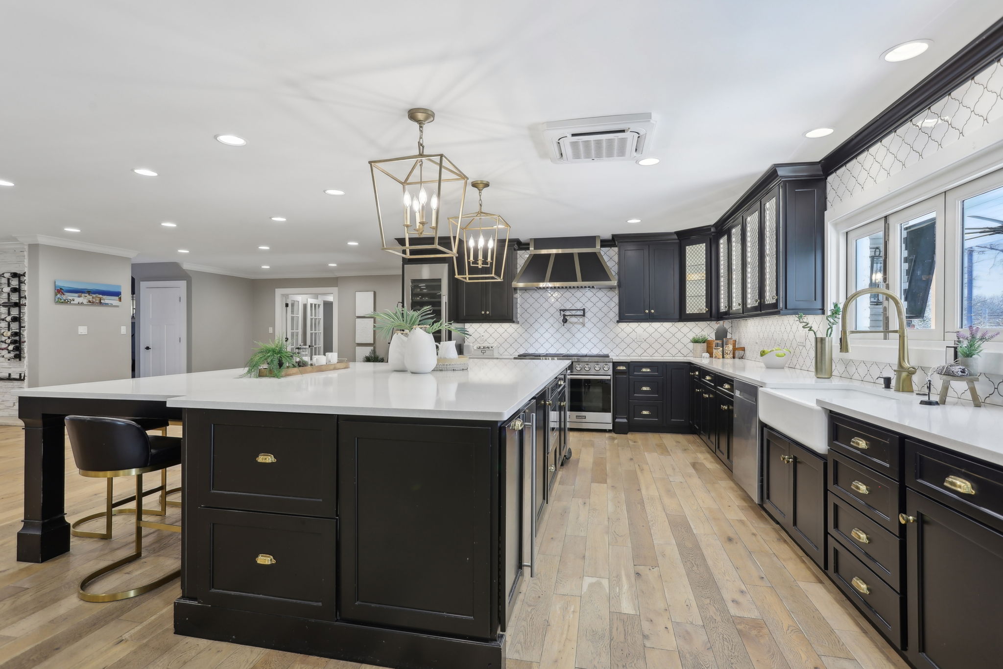 Modern kitchen featuring black cabinetry, a large white island, and sleek appliances. Bright lighting enhances the spacious design.
